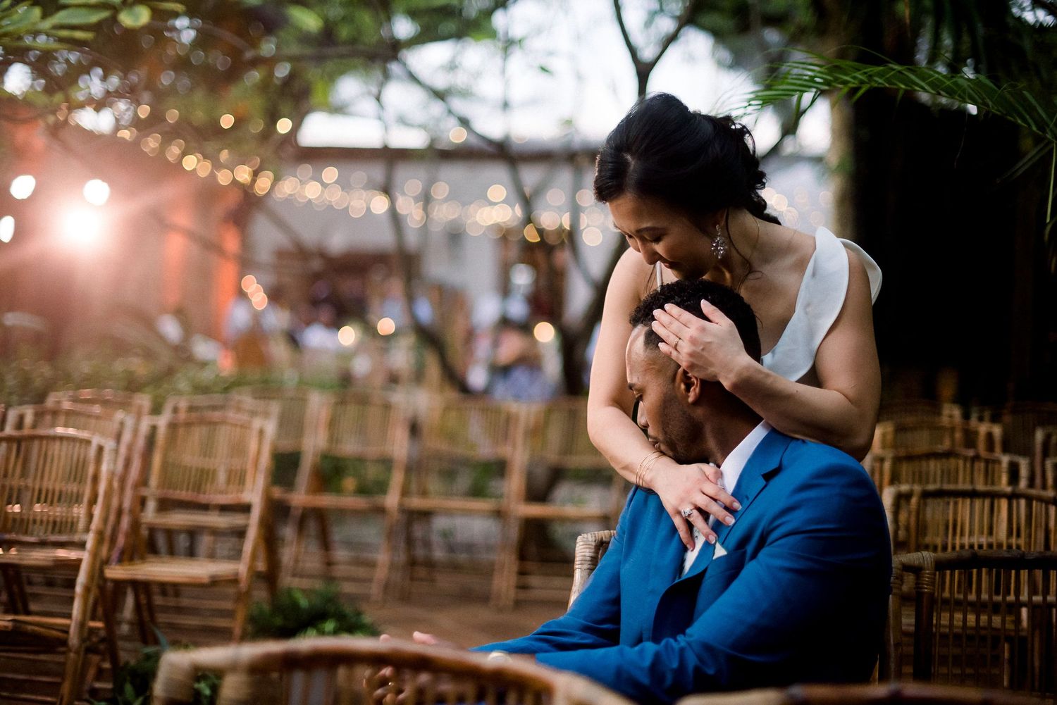 A romantic embrace between a couple during an outdoor wedding ceremony with wooden chairs.