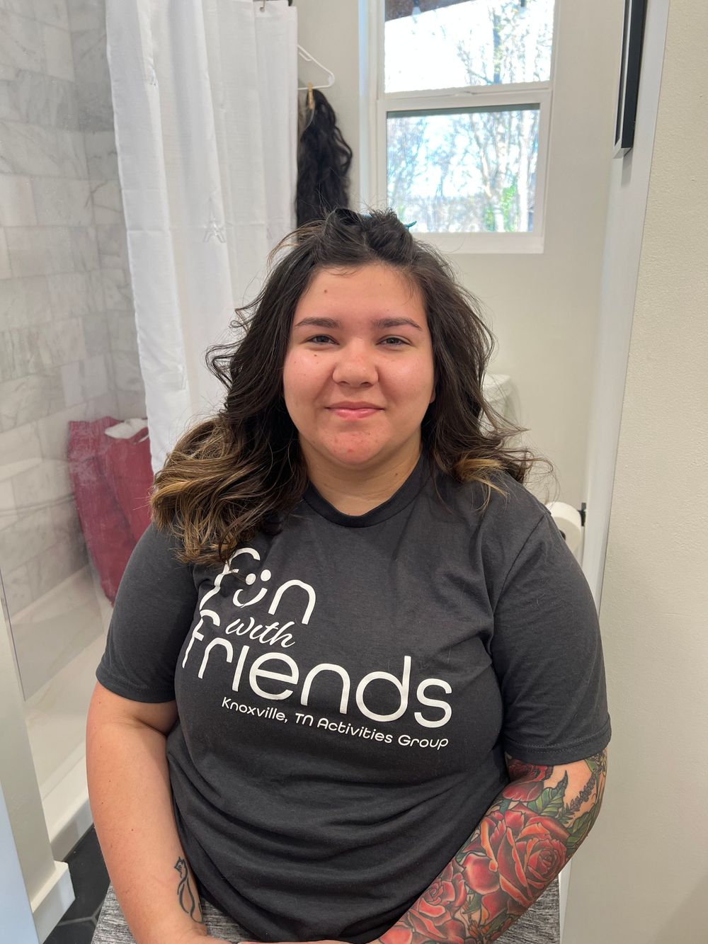 Person wearing black t-shirt with 'Friends' text sitting by window.