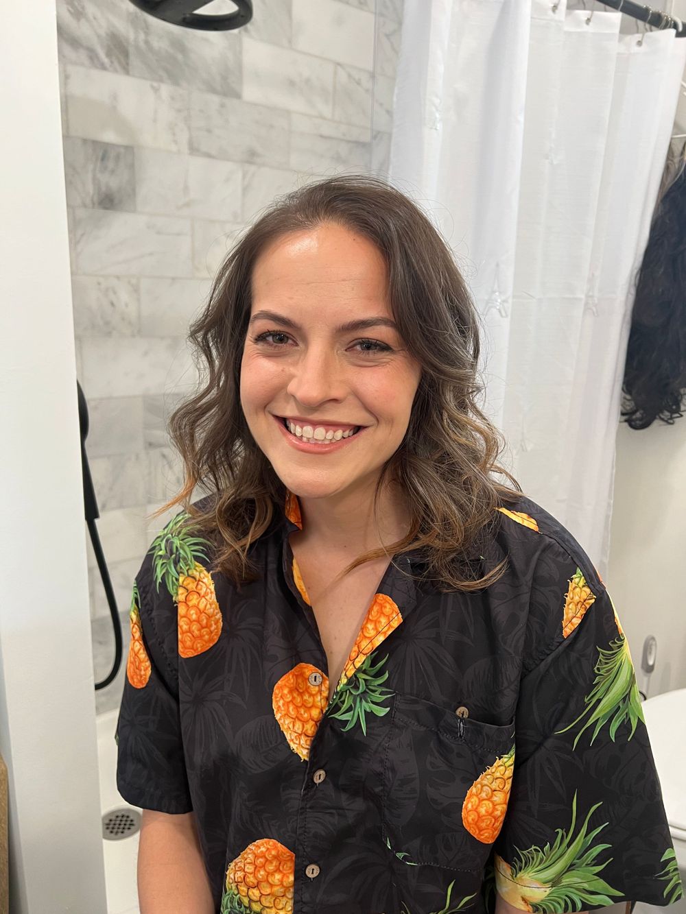 Person in black pineapple print button-up shirt smiling at camera.
