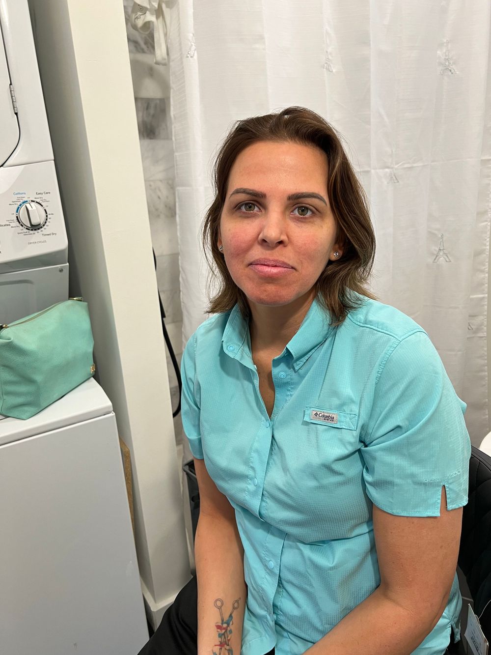 Healthcare worker in light blue uniform taking selfies in medical setting.