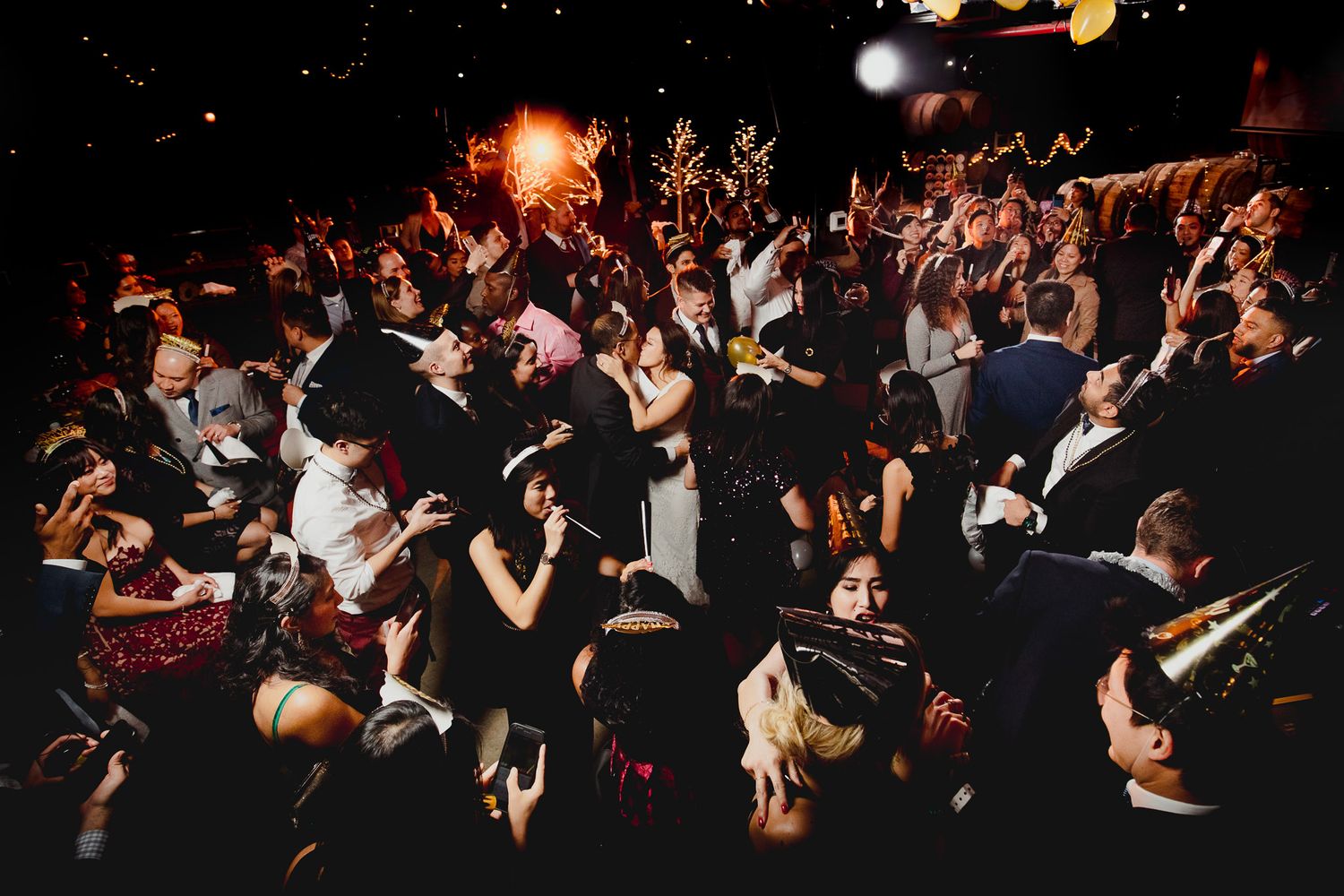 A crowded dance floor filled with celebrating wedding guests under party lights.