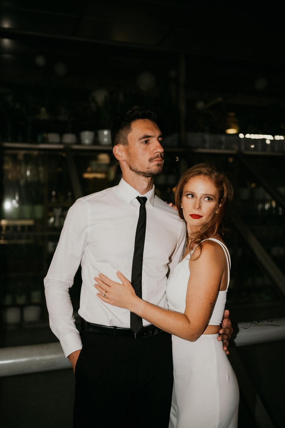 An elegant couple in black and white formal wear pose during an evening photoshoot.