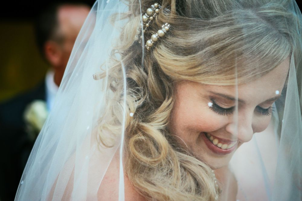 Close-up of a radiant bride wearing a delicate veil and sparkling hair accessories.