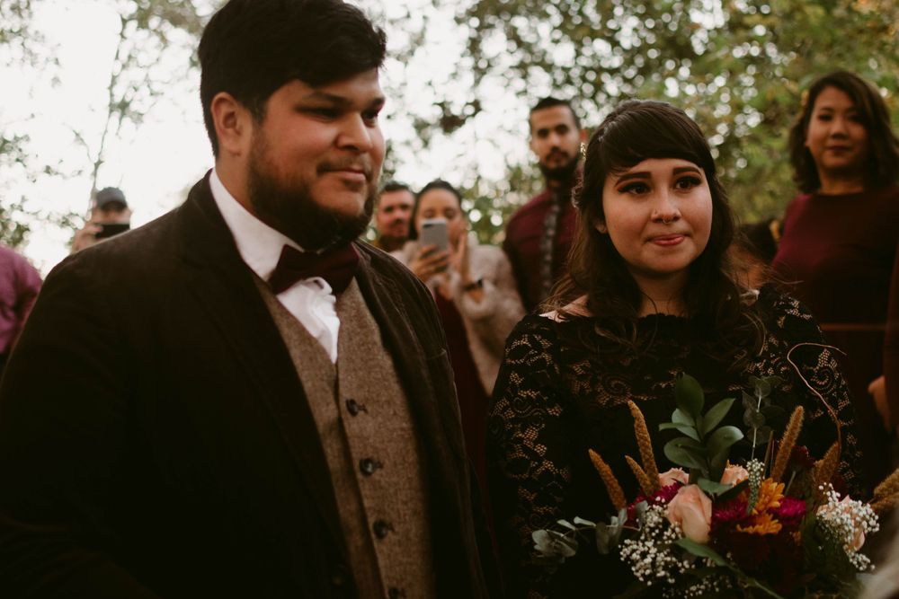 A couple celebrates during their autumn woodland wedding ceremony.