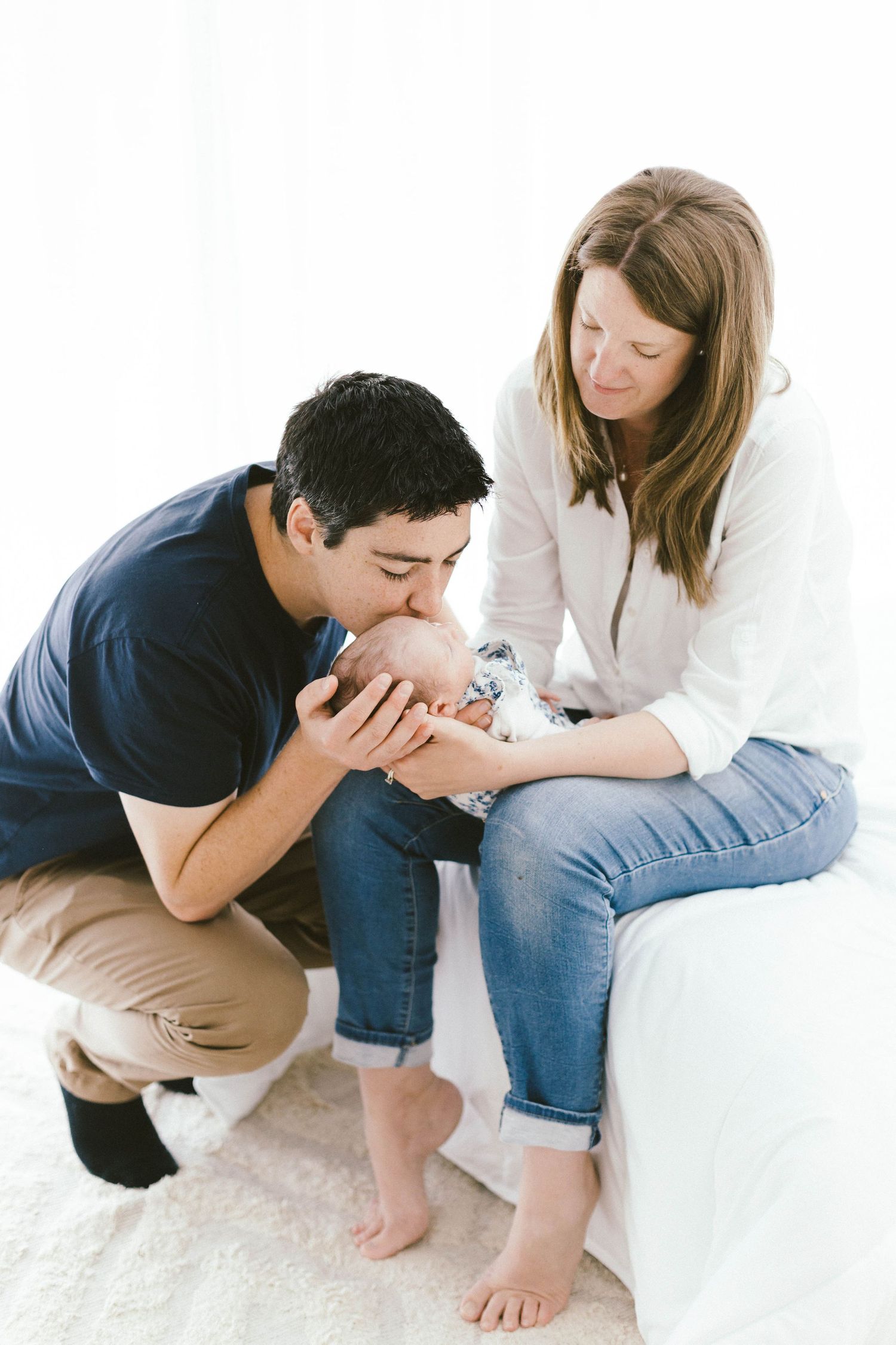 Family sharing an intimate moment together on white furniture.