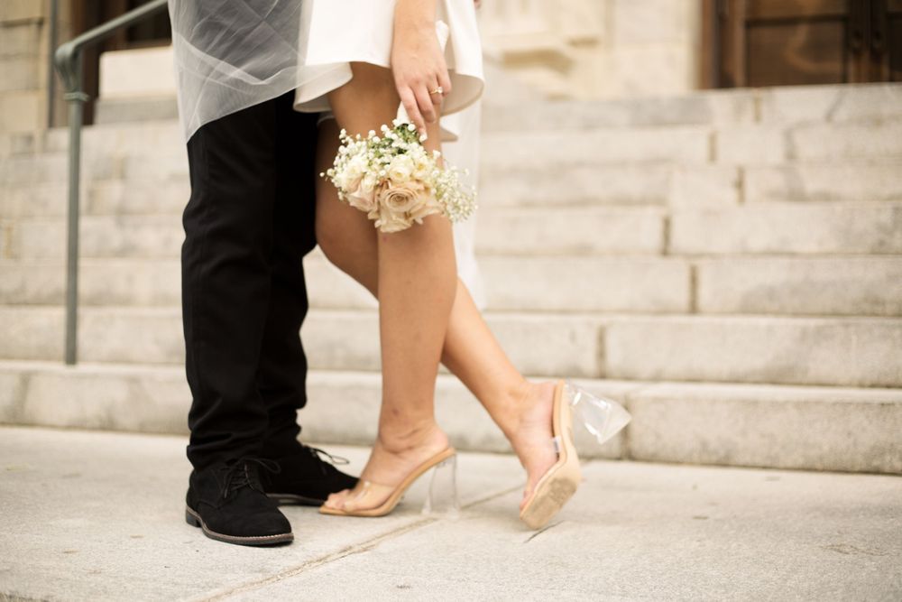 Close-up of couple's feet and bouquet on stone steps during wedding shoot.