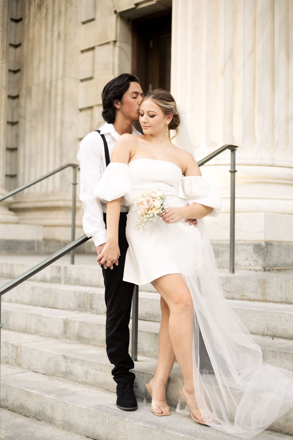 A tender wedding moment captured on grand stone steps with elegant architectural details.