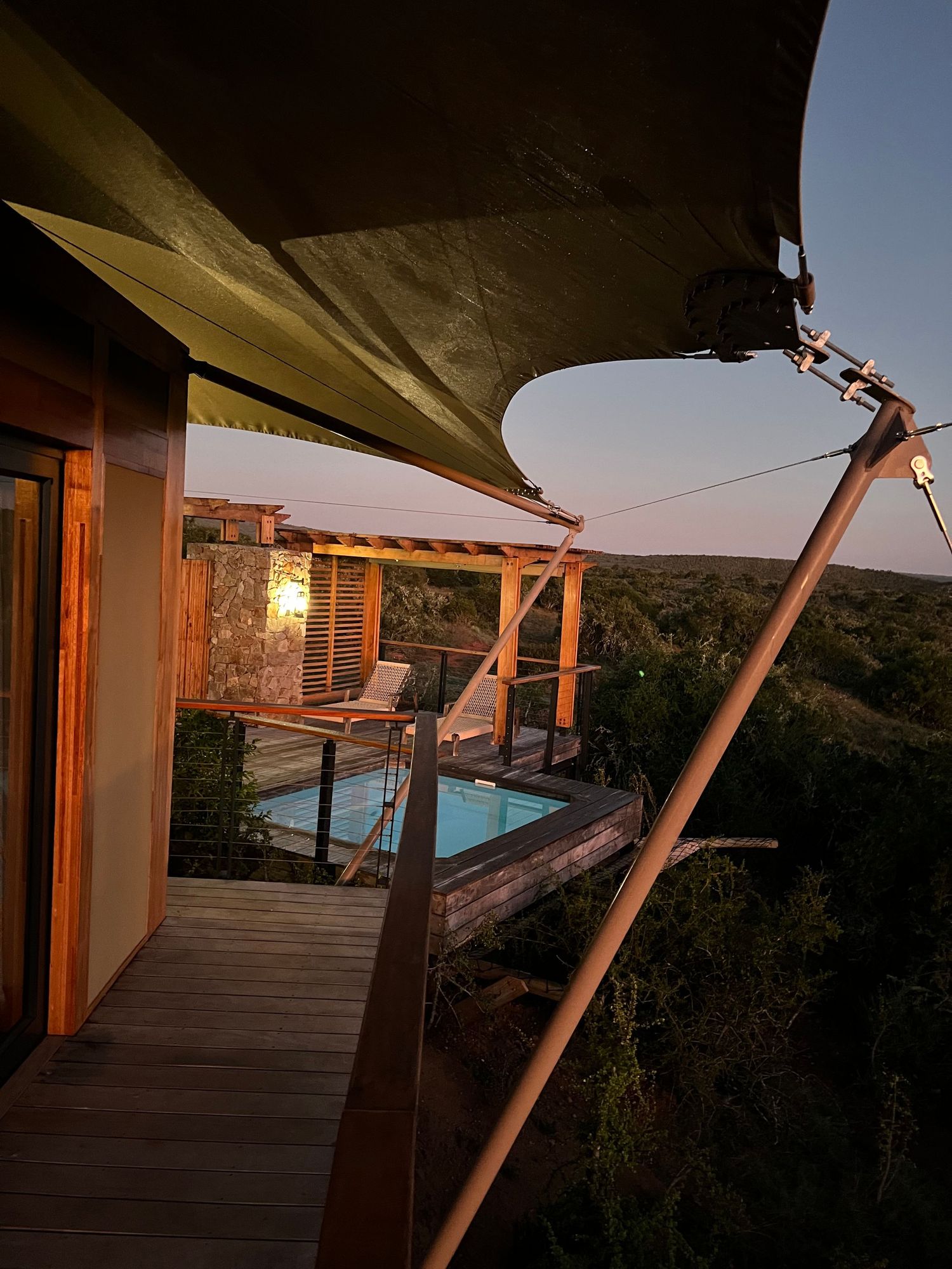Wooden deck with canvas awning supports at sunset.