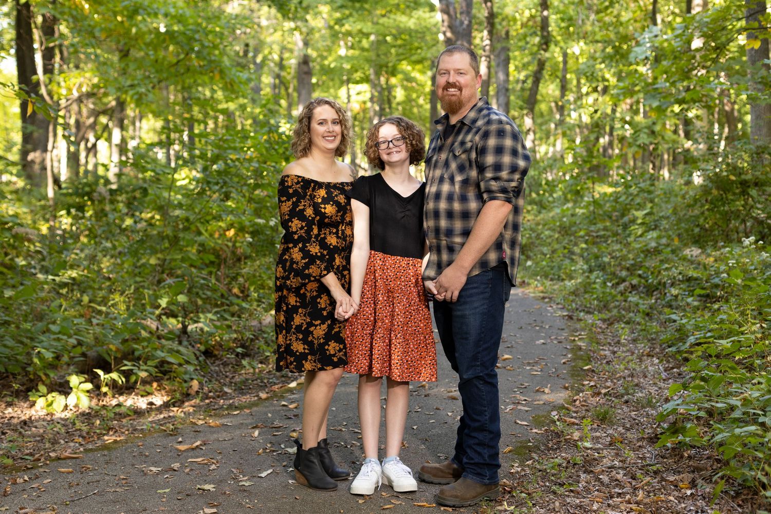 Small family of three smile happily for their family portraits.