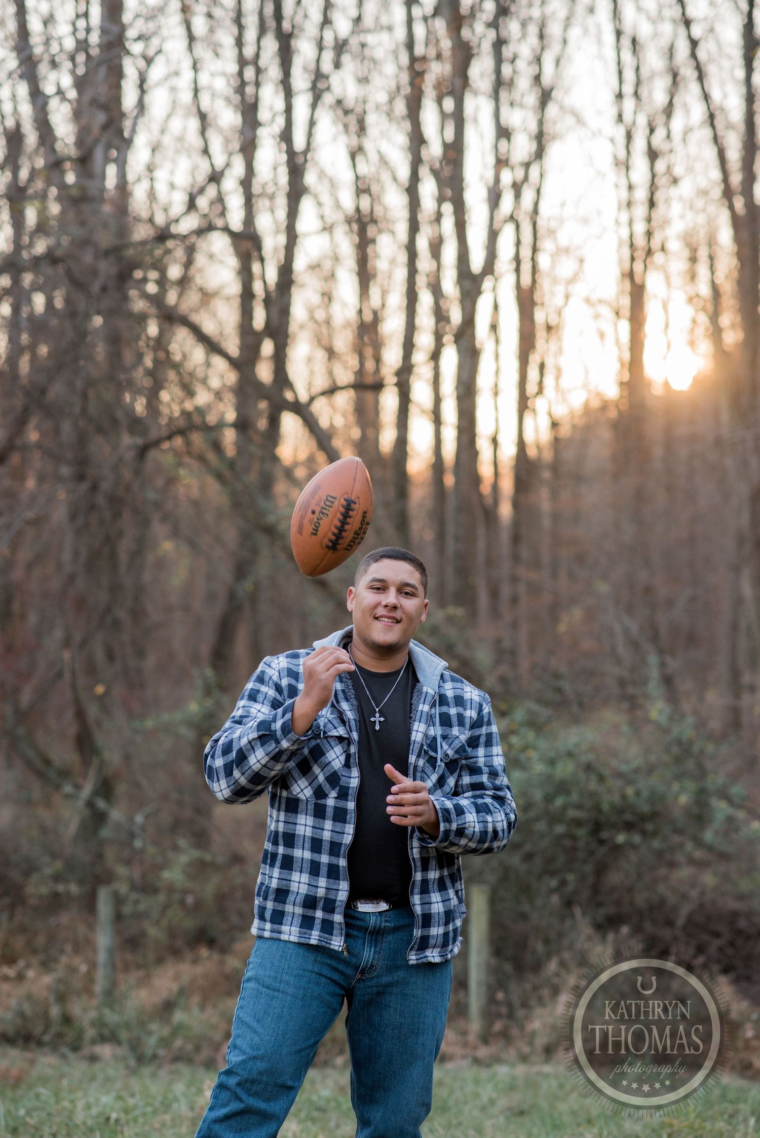 Someone tosses an NFL football while wearing plaid against a sunset forest backdrop.