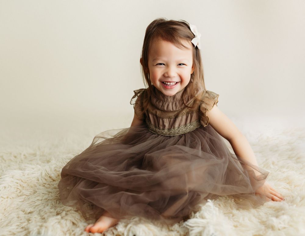 A little Asian girl in a brown dress smiling. Greenville, SC newborn photographer, Easley, SC Newborn photographer