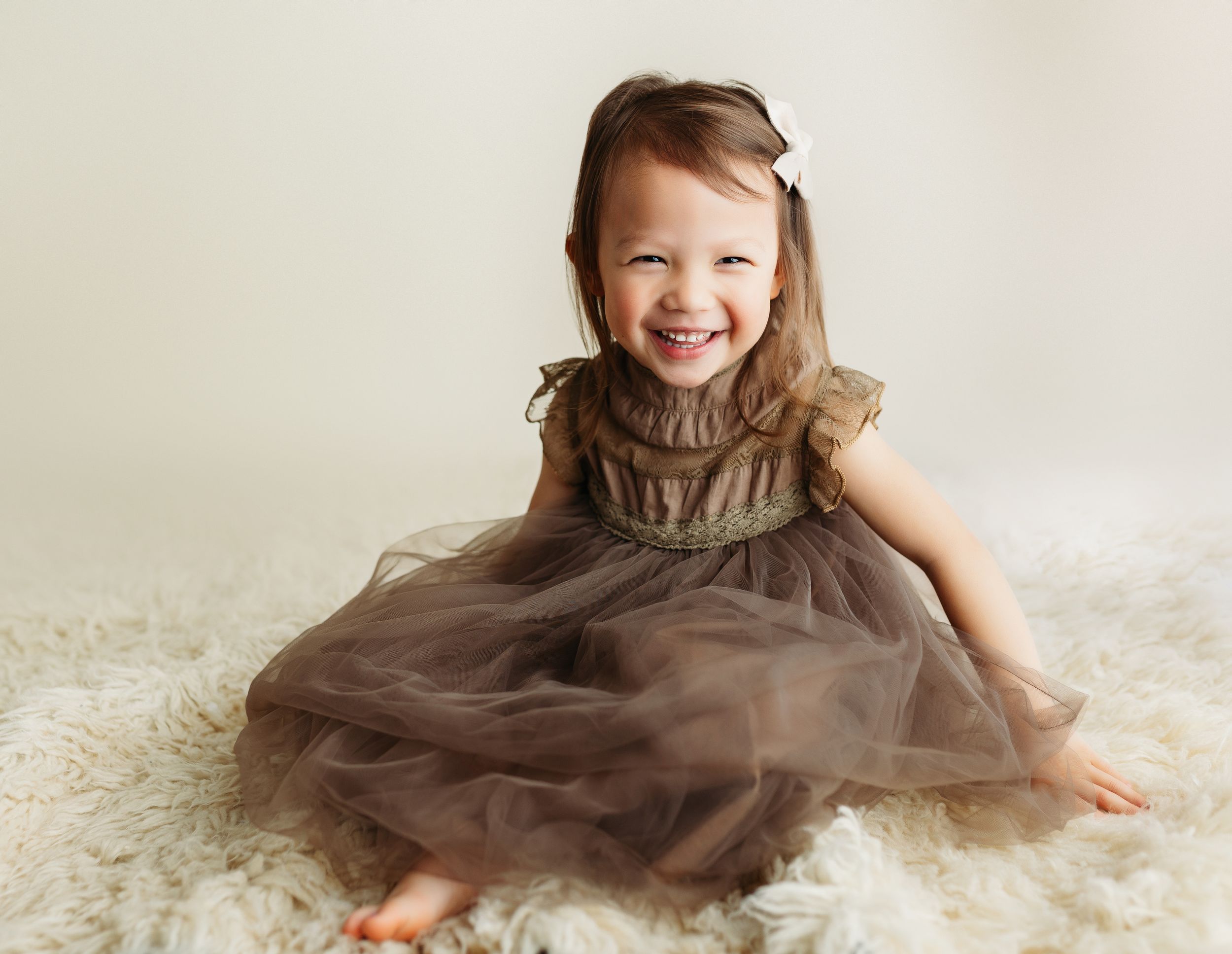 A little Asian girl in a brown dress smiling. Greenville, SC newborn photographer, Easley, SC Newborn photographer