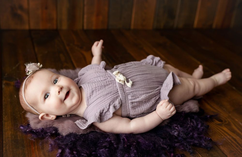 Milestone session of a little girl on her back smiling at the camera. Greenville, SC newborn photographer, Easley, SC Newborn photographer