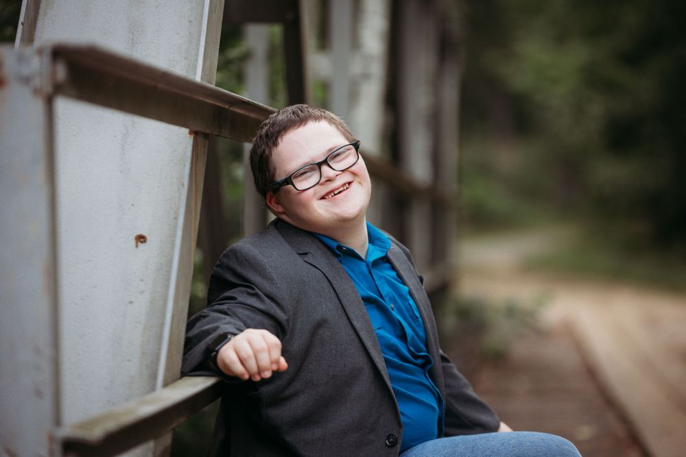 A Down Syndrome young man on a bridge smiling for his senior session. Greenville, SC newborn photographer, Easley, SC Newborn photographer