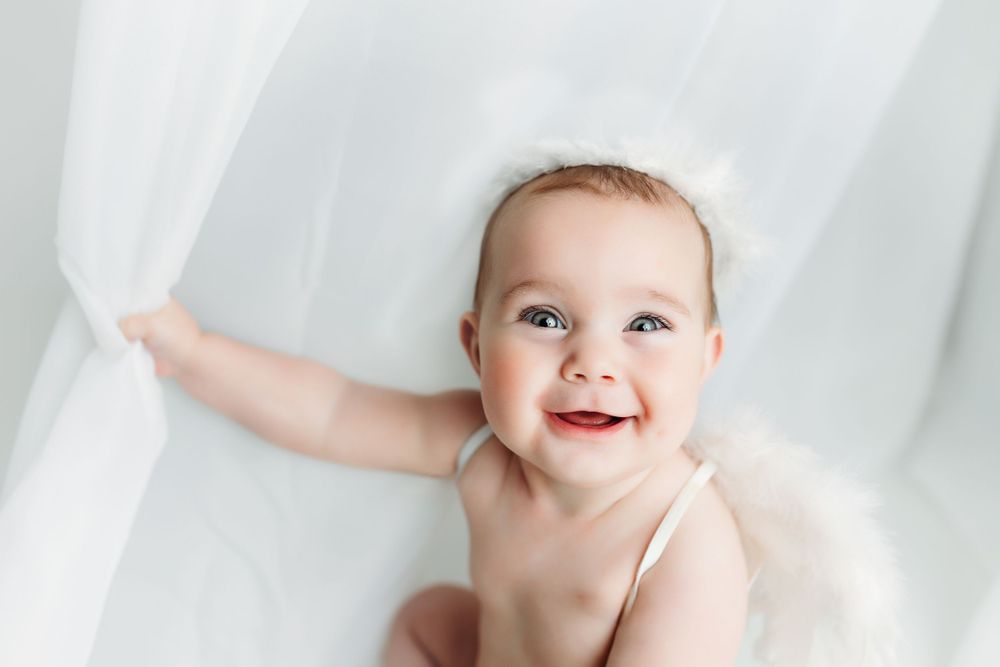 A little girl wearing wings and playing peek-a-boo. Greenville, SC newborn photographer, Easley, SC Newborn photographer