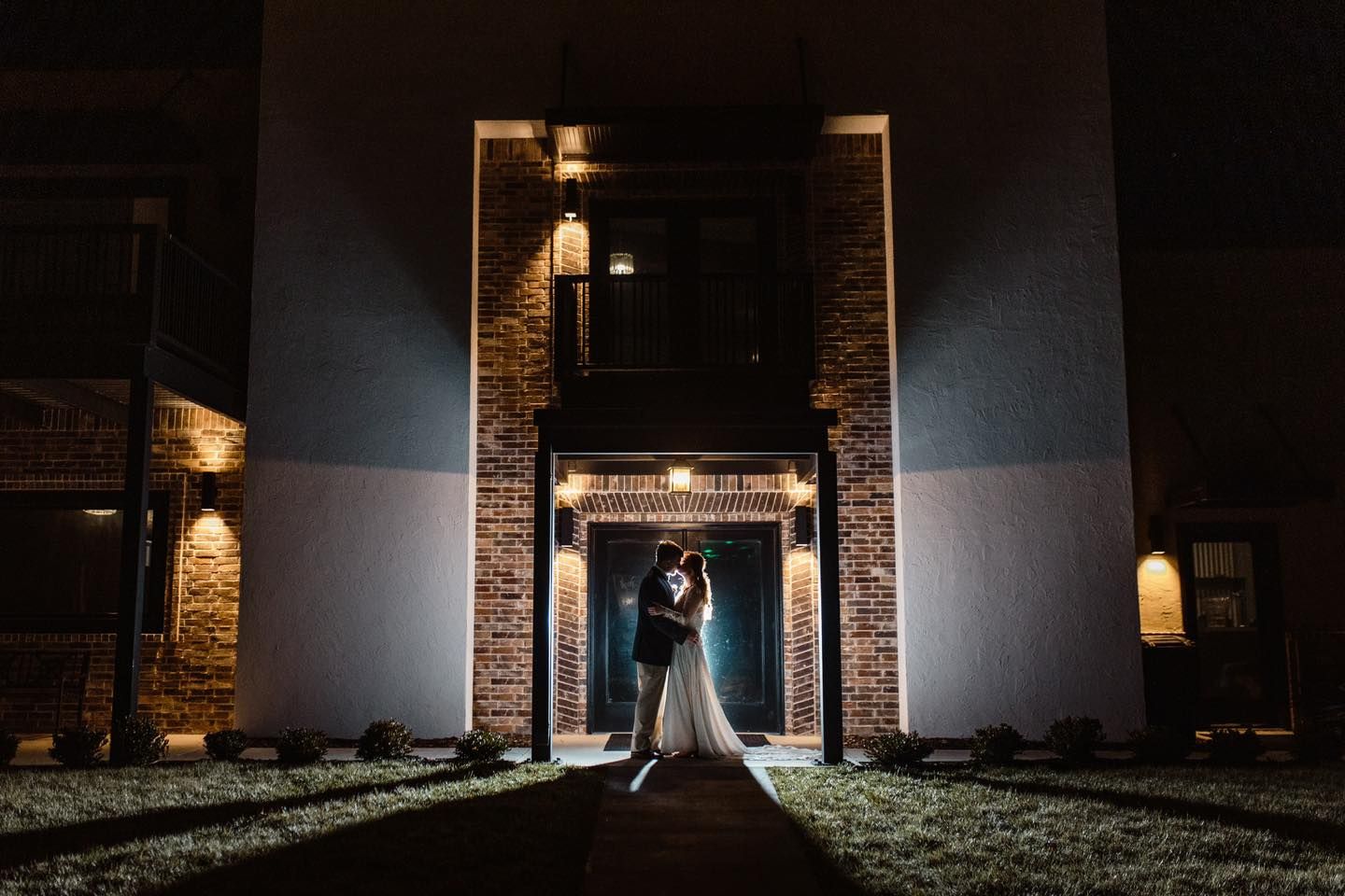 Dramatic nighttime architectural lighting on stone and metal building entrance.