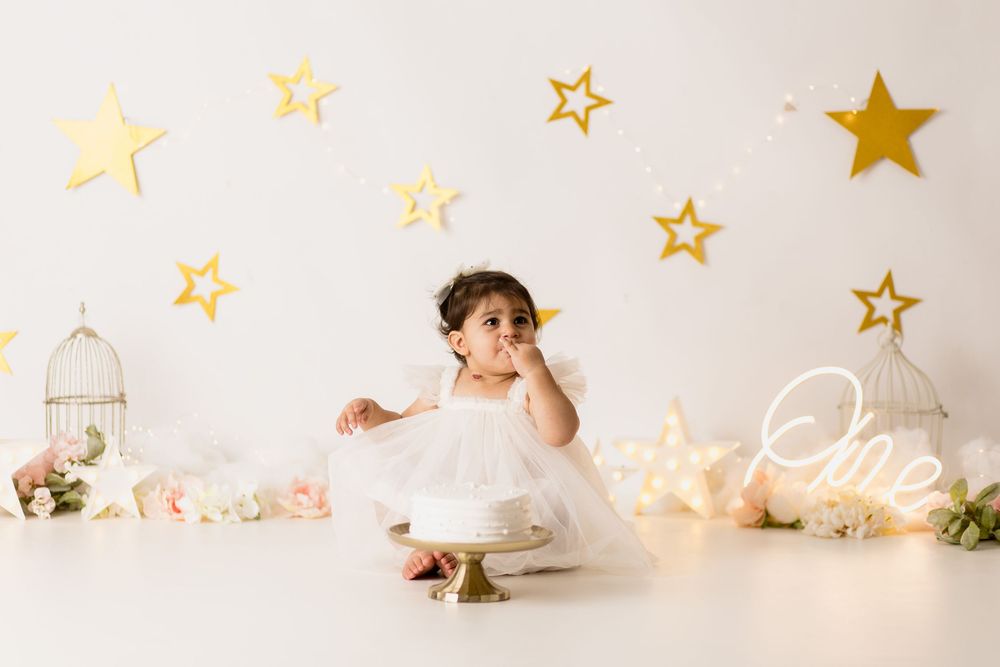 Baby in white dress surrounded by gold stars and fairy lights for milestone photo iowa photographer, davenport photography, bettendorf photo