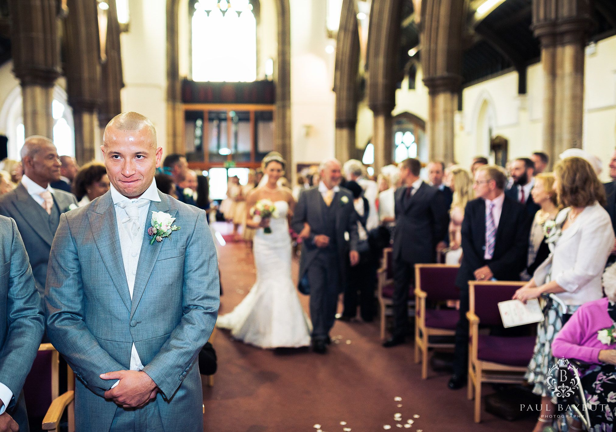 Traditional church wedding ceremony with guests seated in wooden pews and decorative floral arrangements.