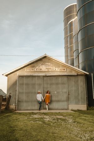 Rustic engagement photo against weathered storage farm building and metal silo.