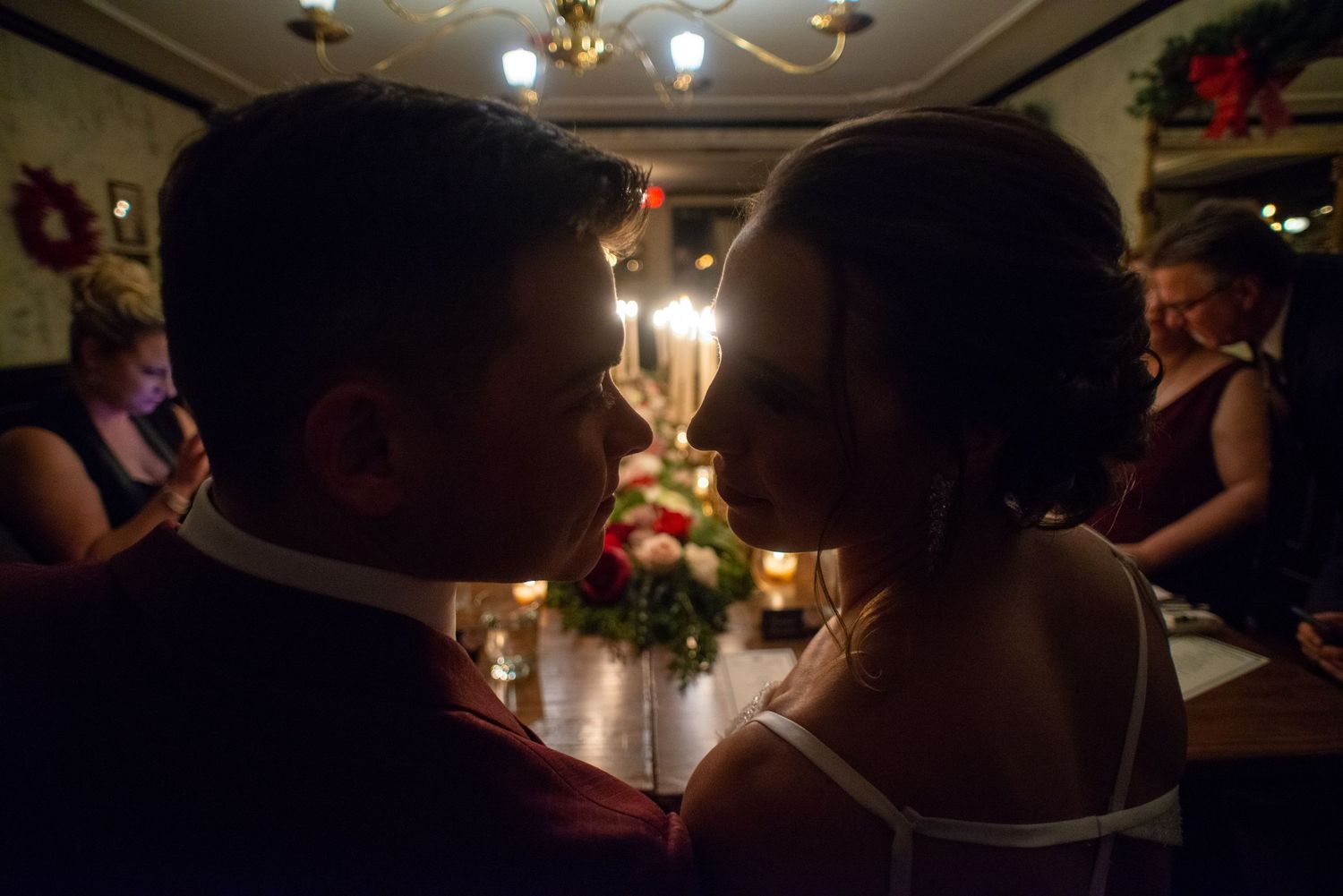 Silhouetted couple shares an intimate moment at a candlelit wedding reception.