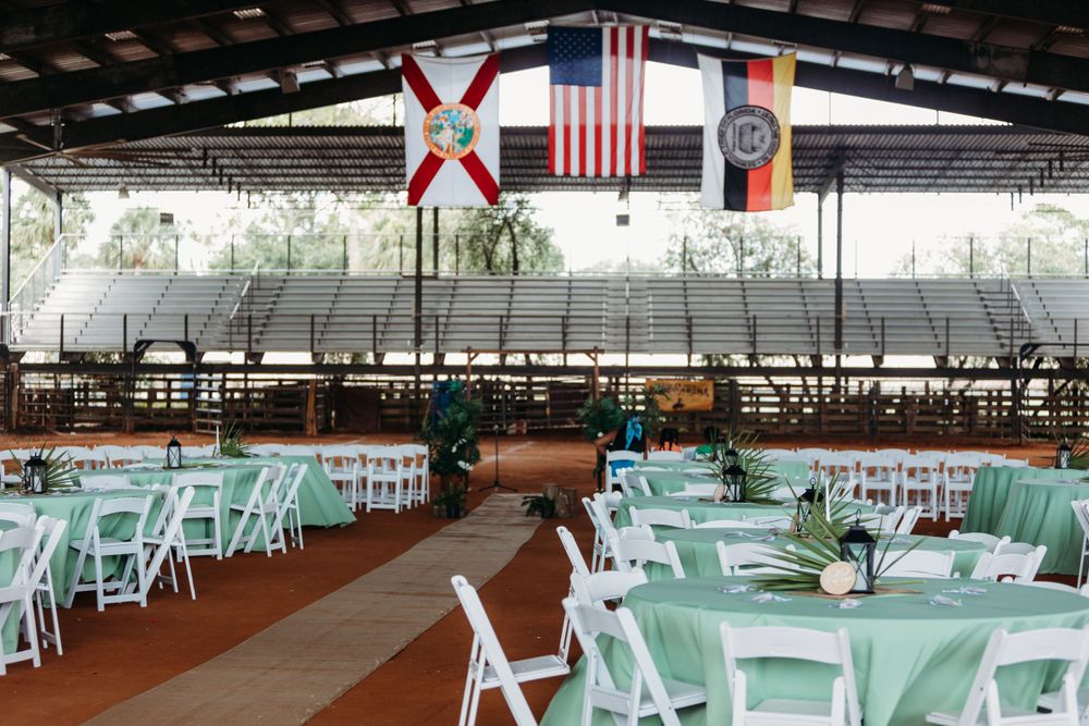 Wedding reception venue with mint green tables and American flags hanging from rustic covered pavilion.
