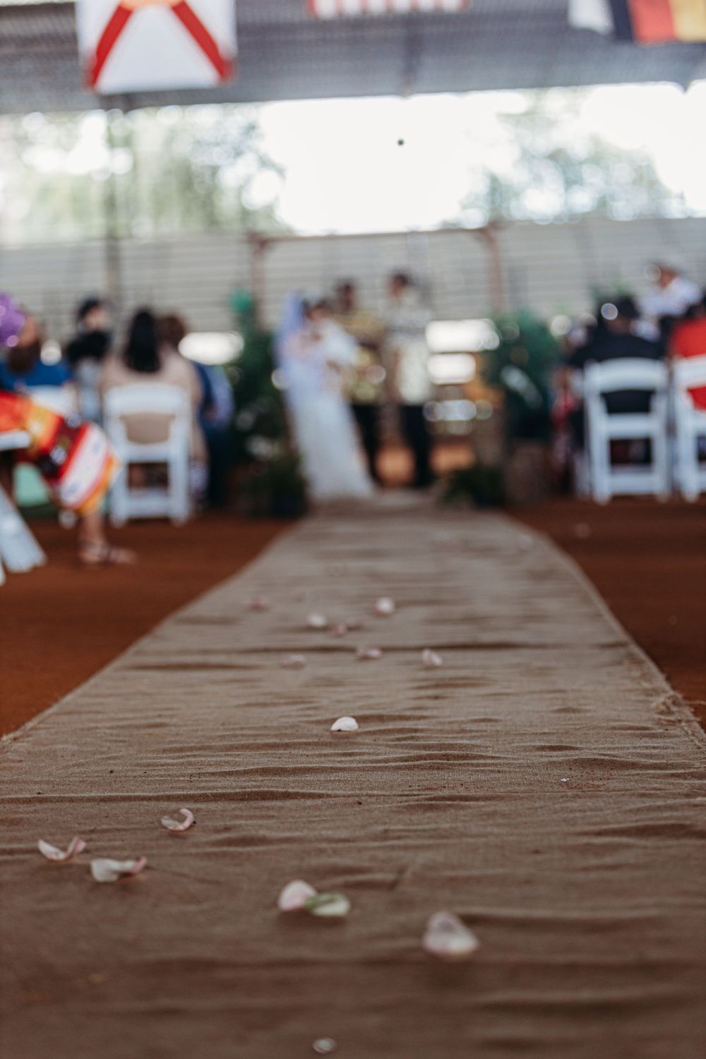 Wedding aisle runner with scattered rose petals in outdoor covered venue.