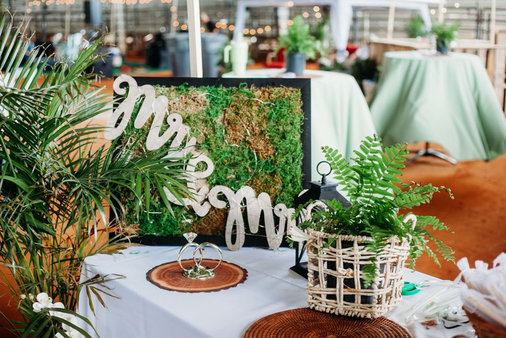 Wedding table decor with Mr & Mrs sign surrounded by tropical plants and greenery.