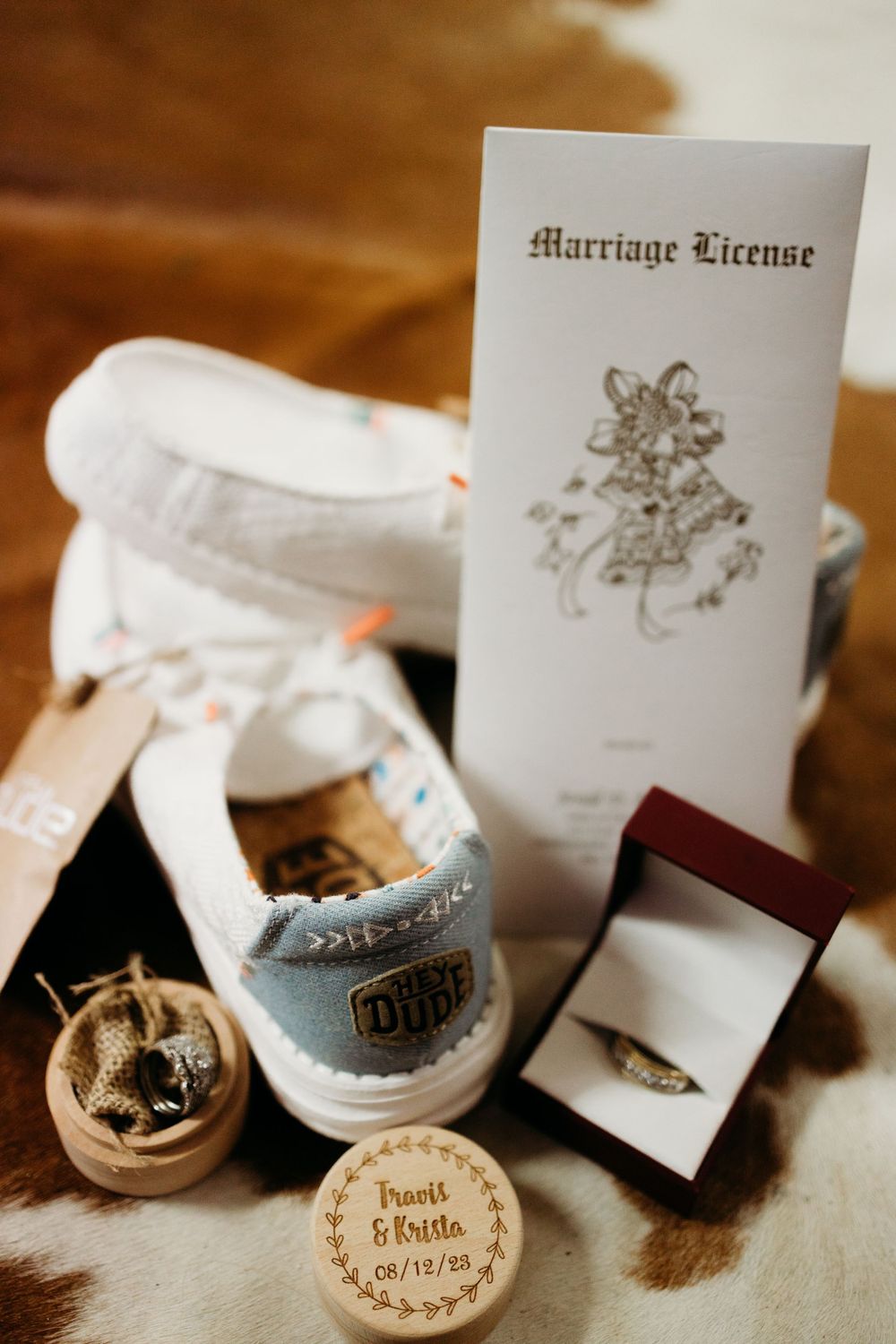 Wedding details including marriage license, shoes, ring box and personalized wooden decoration.