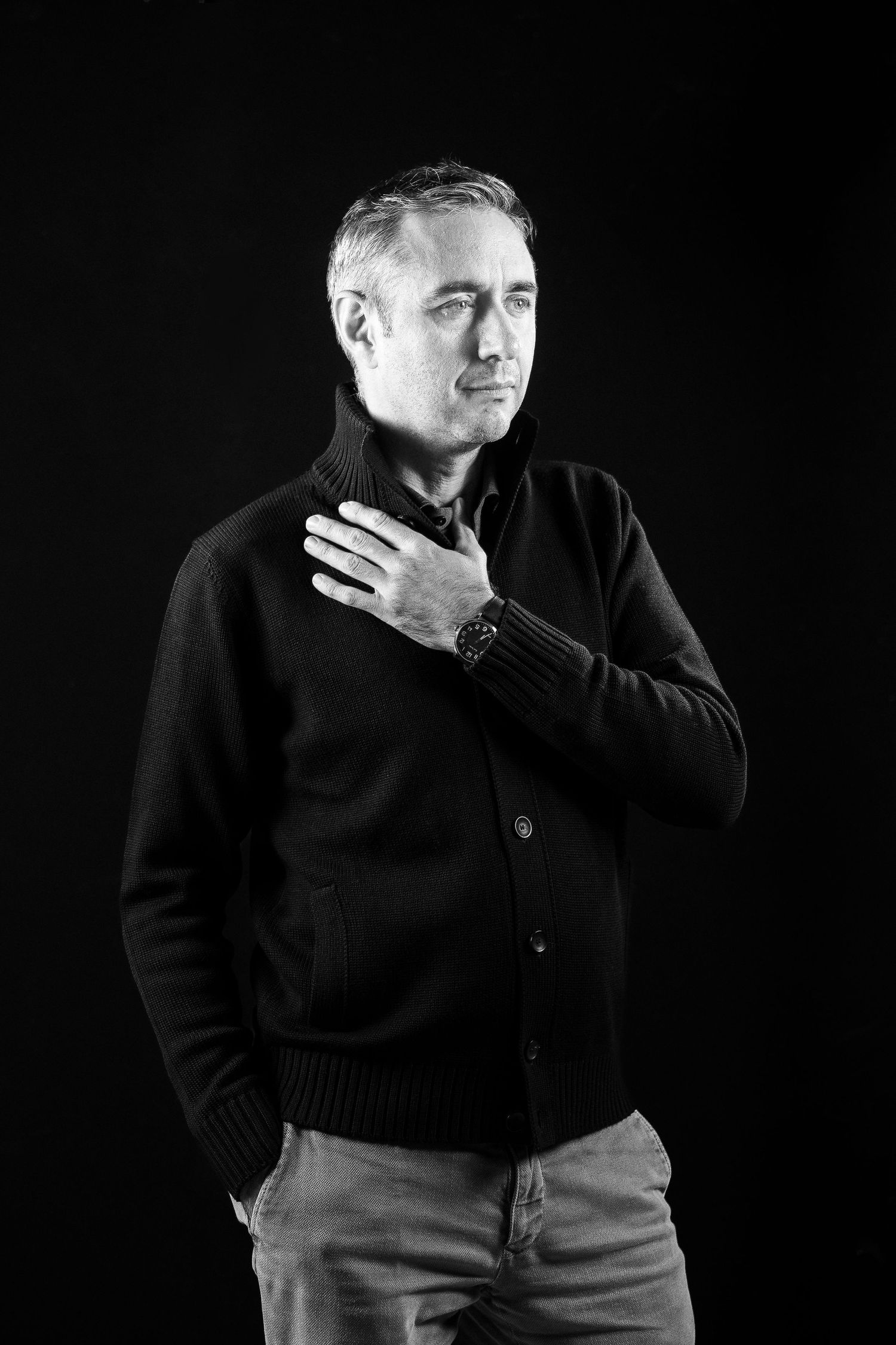 Black and white portrait of person in dark sweater against black background.