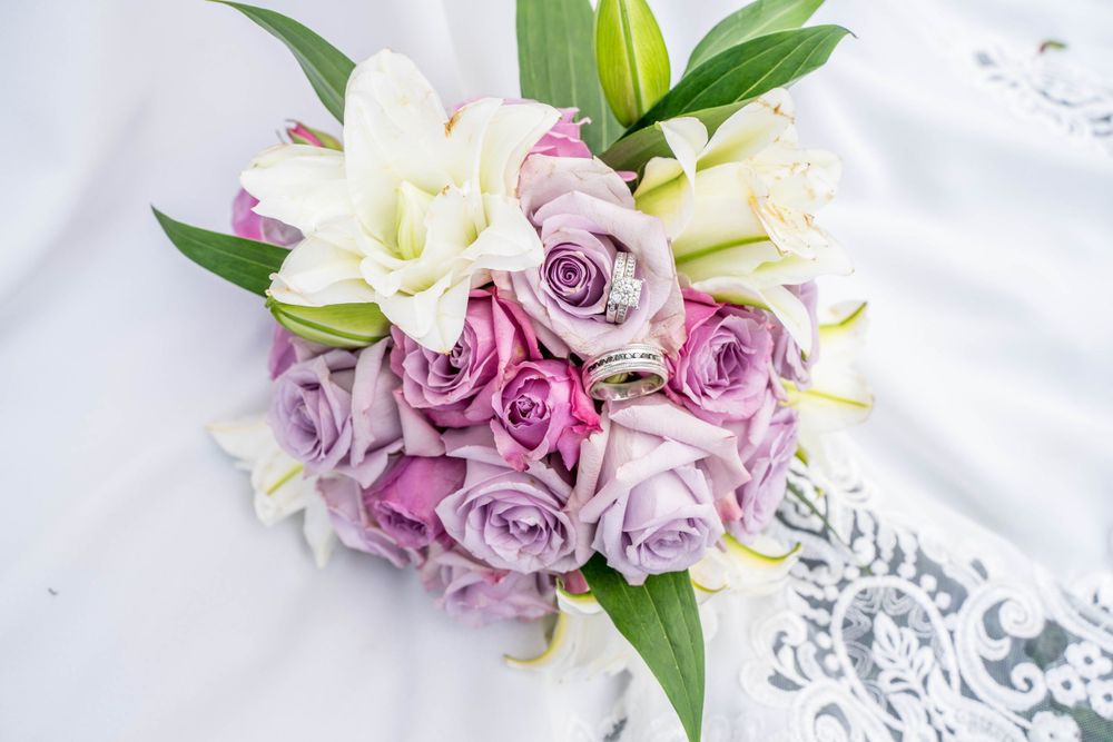 A wedding bouquet featuring white and purple roses arranged in an elegant cascade style.