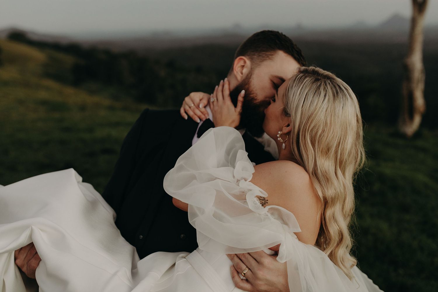 Intimate wedding portrait against scenic mountain backdrop at golden hour.