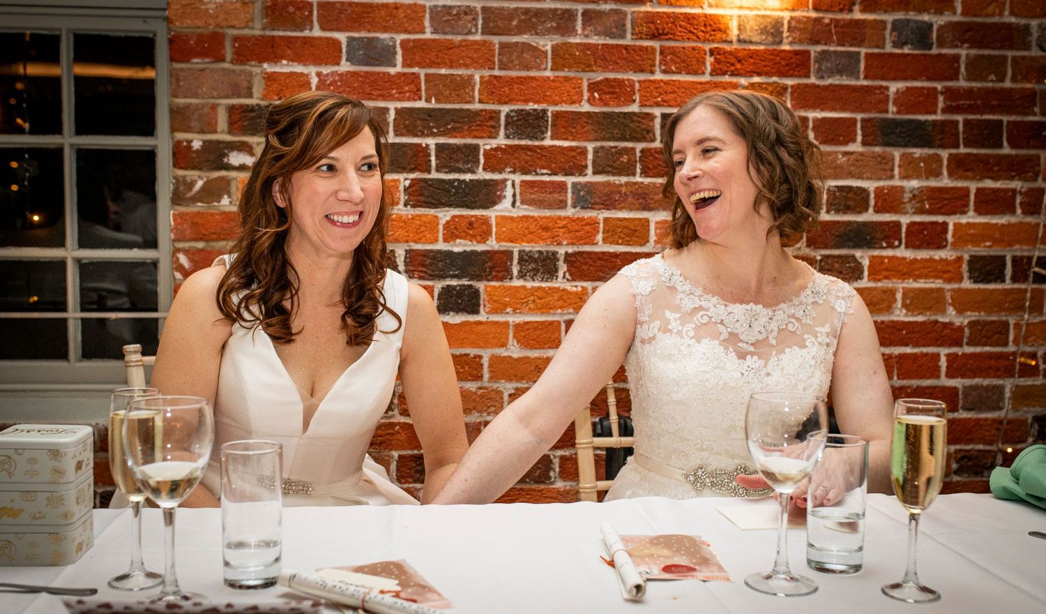 Wedding reception dining setup with brick walls and string lights creating an intimate atmosphere.