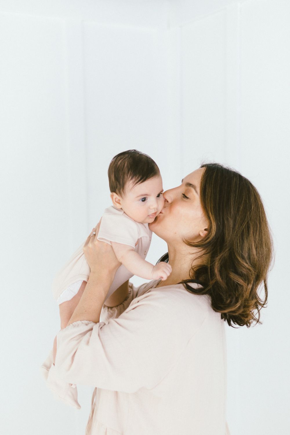 A tender moment between parent and baby against a white backdrop.