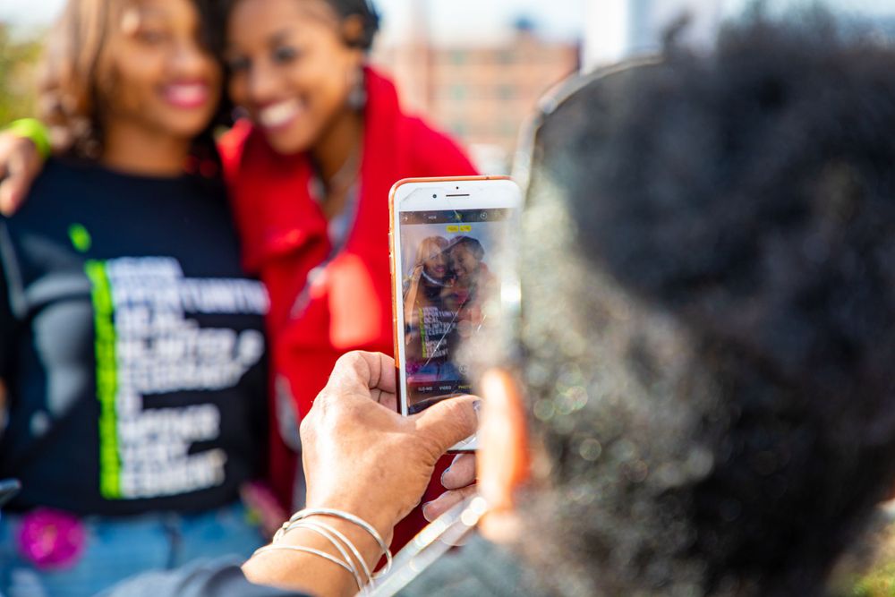 Someone taking a selfie photo on a smartphone outdoors on a sunny day.