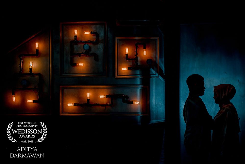 Silhouetted couple against warm candlelit wall boxes creating romantic ambiance.