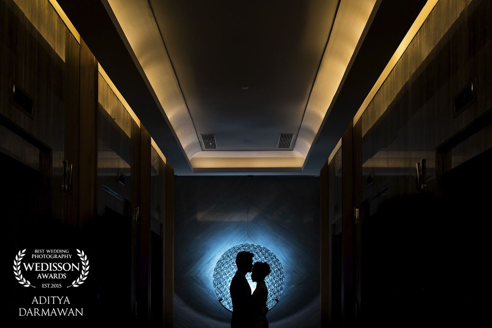 Silhouetted couple in a dramatic hallway with circular blue light creating a romantic atmosphere.
