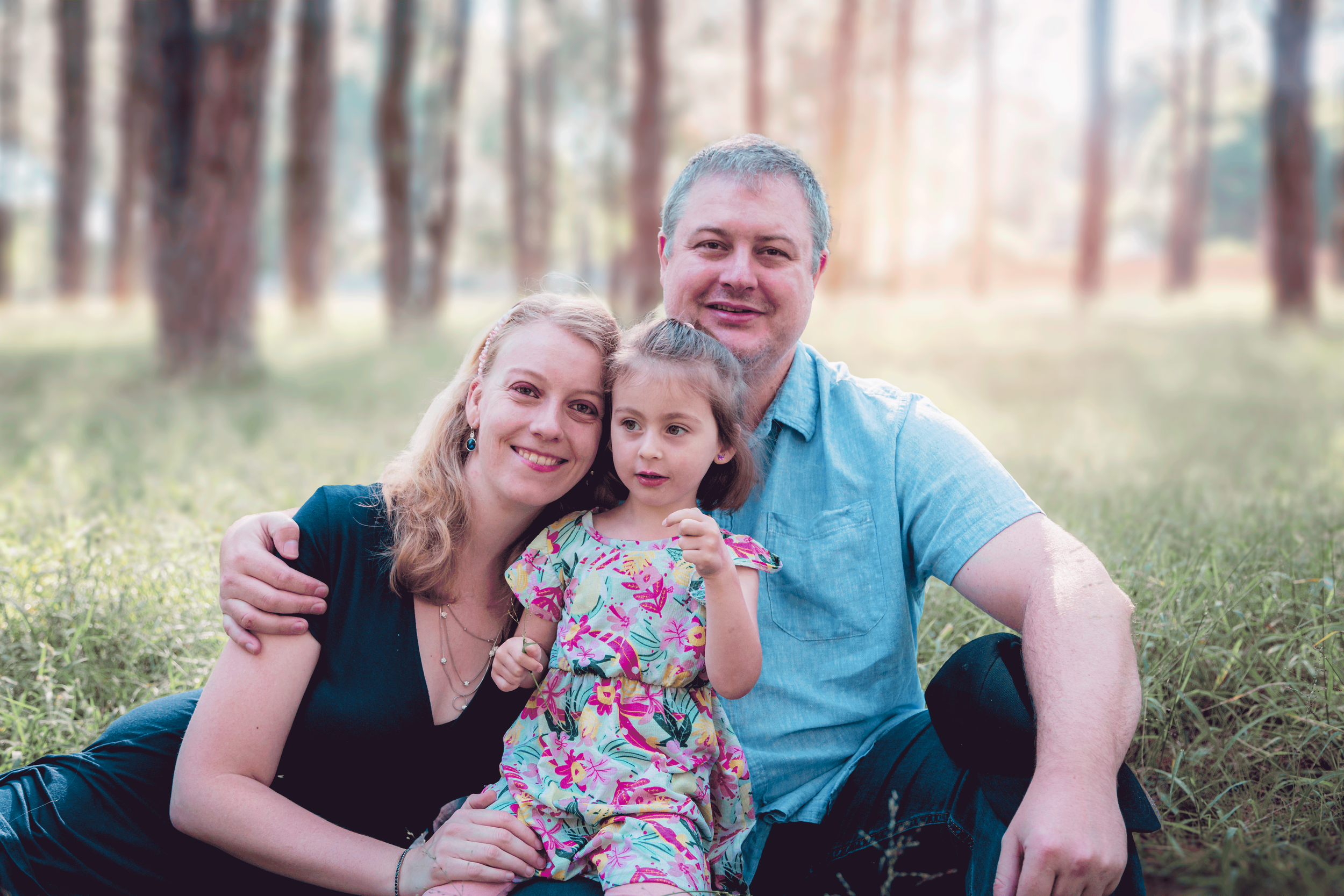 Mom and Dad and Daughter sitting side-by-side in the forest