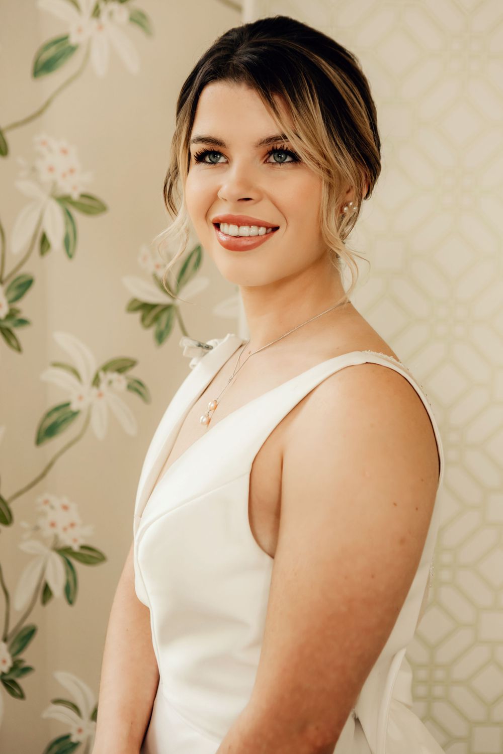 Portrait in classic bridal style against floral wallpaper backdrop.