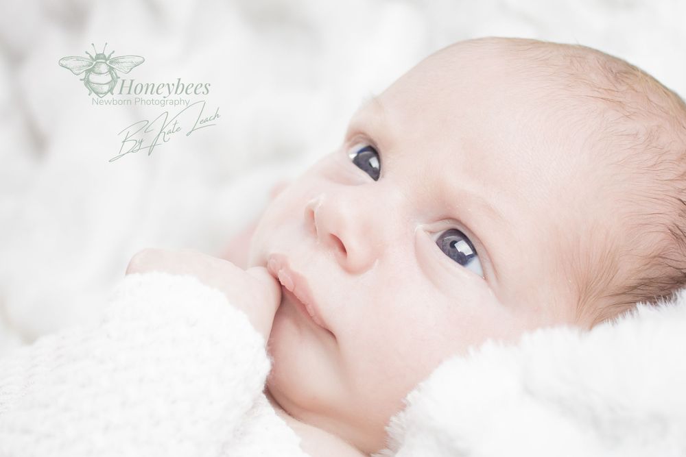 baby boy laid on his back hand in mouth with white background and bay sleep suite