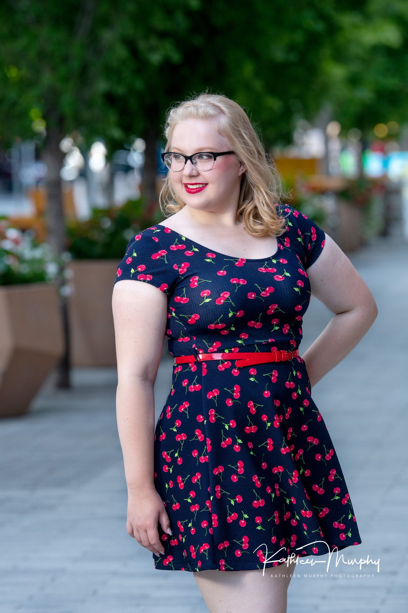 Kathleen Murphy Photography picture of a teen girl in a navy dress with cherry pattern.