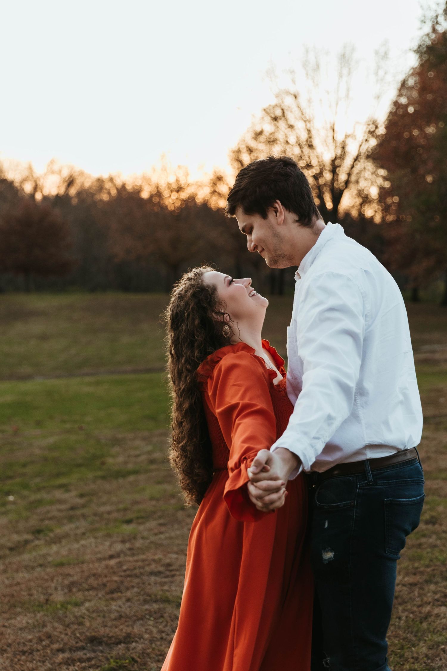 Romantic sunset photoshoot in a field showing intimate moments between a couple.