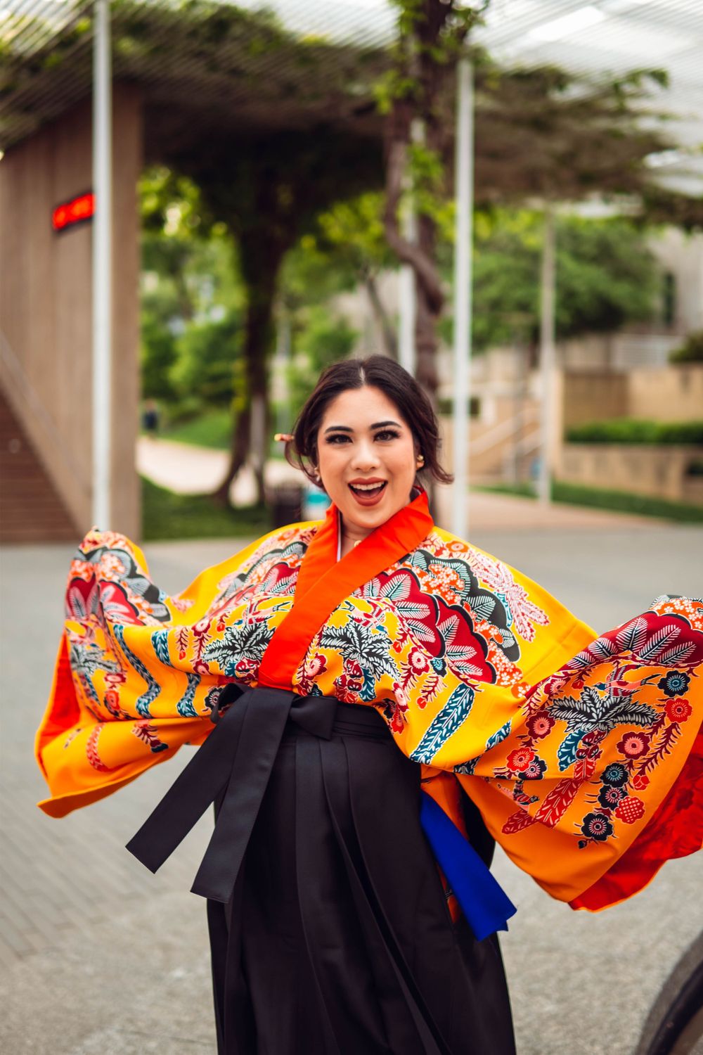 Person in graduation gown twirling to show off vibrant orange and black cultural stole.