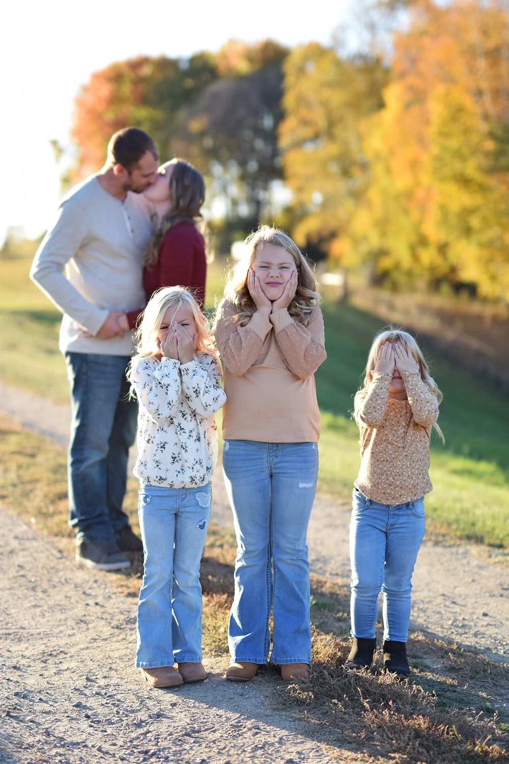 Candid family moments captured in golden sunlight on dirt path during autumn.
