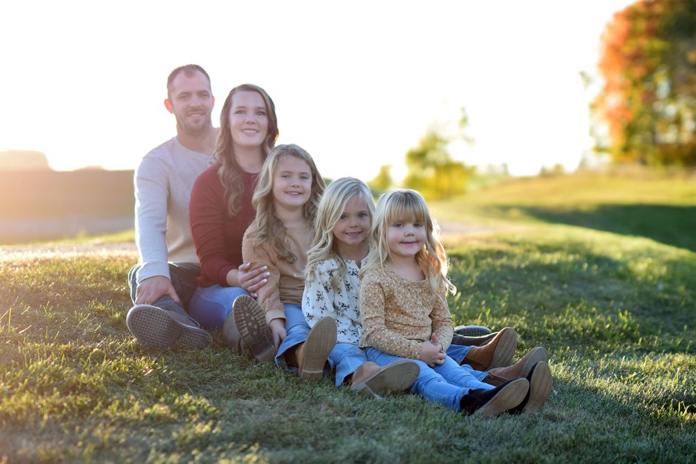 Family group photo session in grassy field during golden hour.