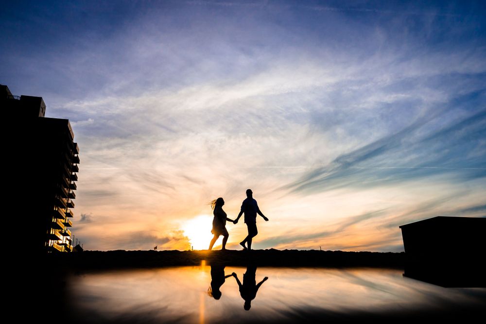 Silhouettes of people against a dramatic sunset sky with clouds.