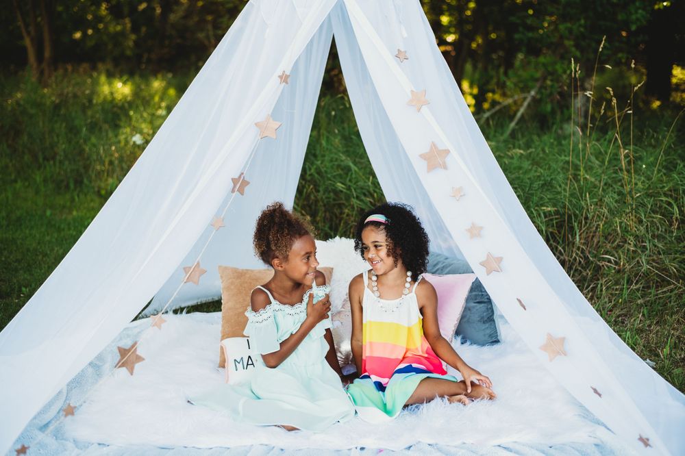 Outdoor photography setup with white teepee tent and scattered flower petals in garden setting.