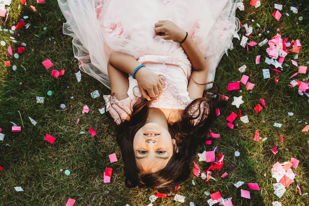 Artistic overhead shot with scattered pink and red rose petals on green grass.