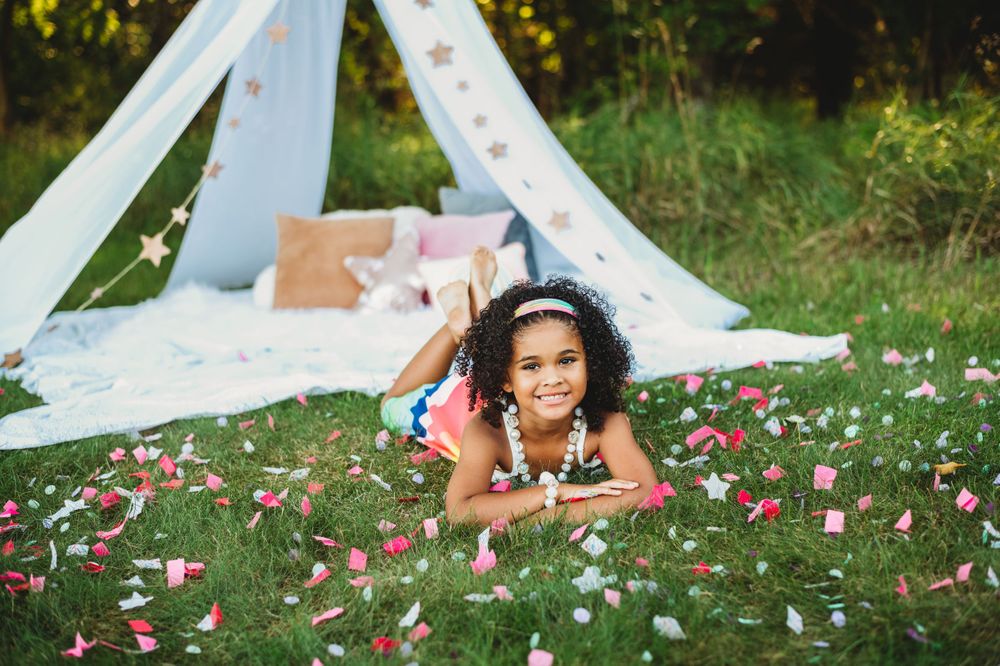 Outdoor photo session with white tent and scattered pink petals on grass.