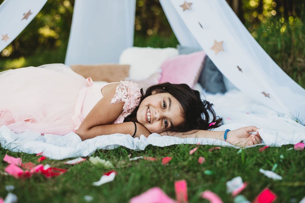 Romantic garden scene with scattered rose petals around a white teepee tent.