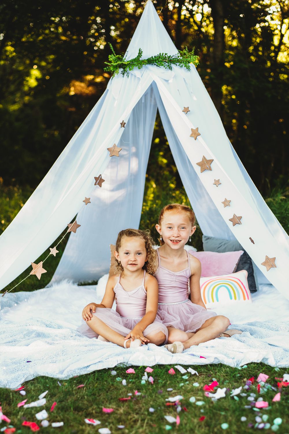 Outdoor photography scene with white teepee tent decorated with star ornaments.